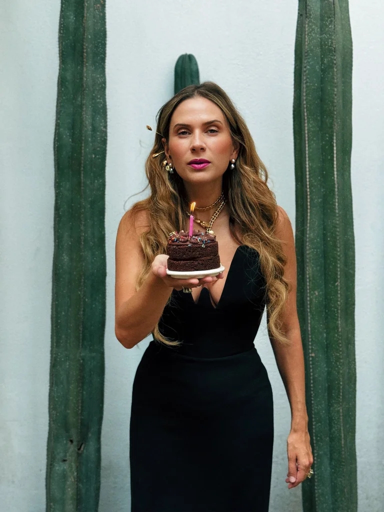 Sahra-Josephine holding a birthday cake between tall cacti