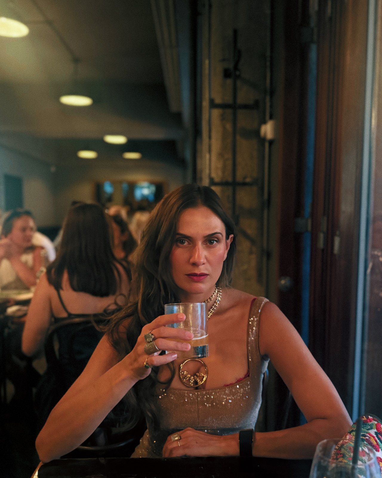 Portrait of Sahra-Josephine Hjorth seated at a bar table holding a glass