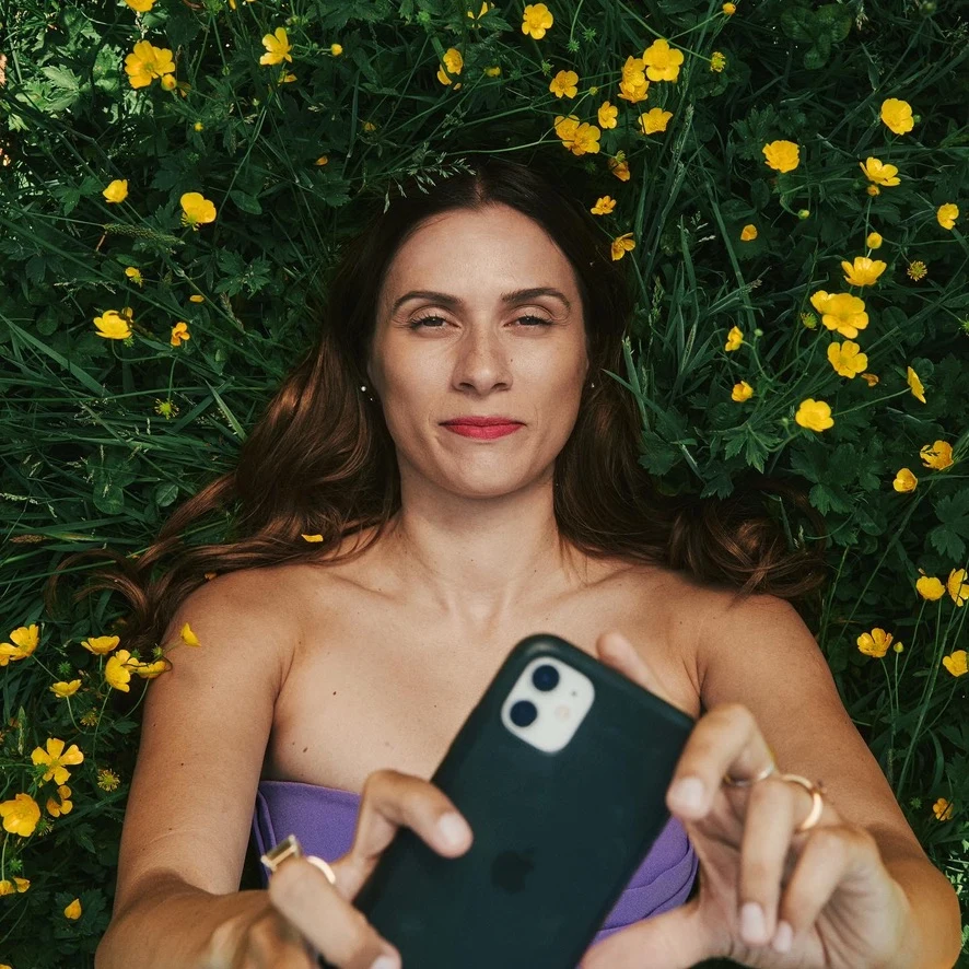 Sahra-Josephine holding a phone among yellow flowers
